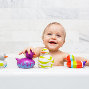 Infant playing with modern rubber duck bath toys.