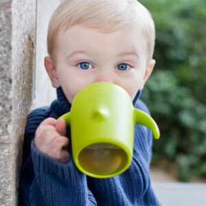 Toddler boy drinking from a green sippy cup.