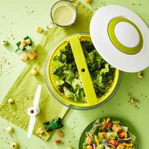 Green salad spinner lifesytle product image top view on a monochromatic set.