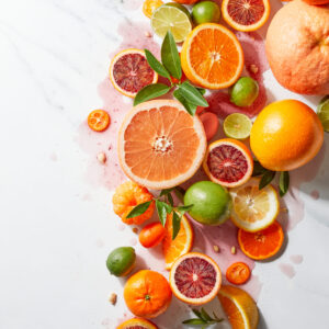 Organically stylized citrus spread featuring a variety of whole and sliced citrus on white marble.