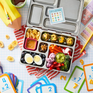 School themed product photography featuring a styled lunchbox packed with a nutritious meal.