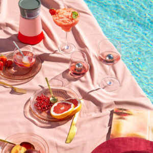 Poolside spread of cocktails and appetizers photographed in natural hard light.