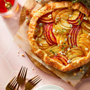 Styled food photography, featuring a baked apple galette on a blush tile surface
